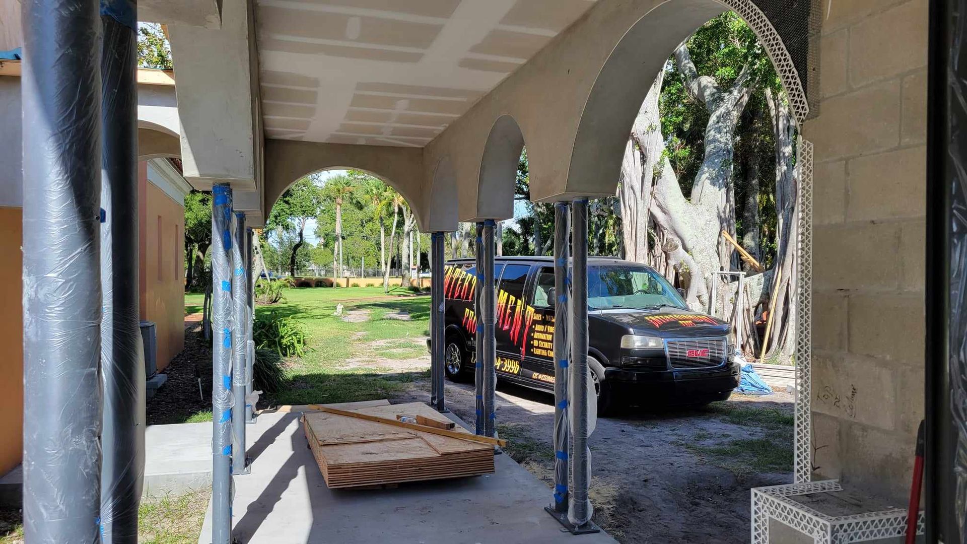 A car is parked under an archway in front of a building under construction.