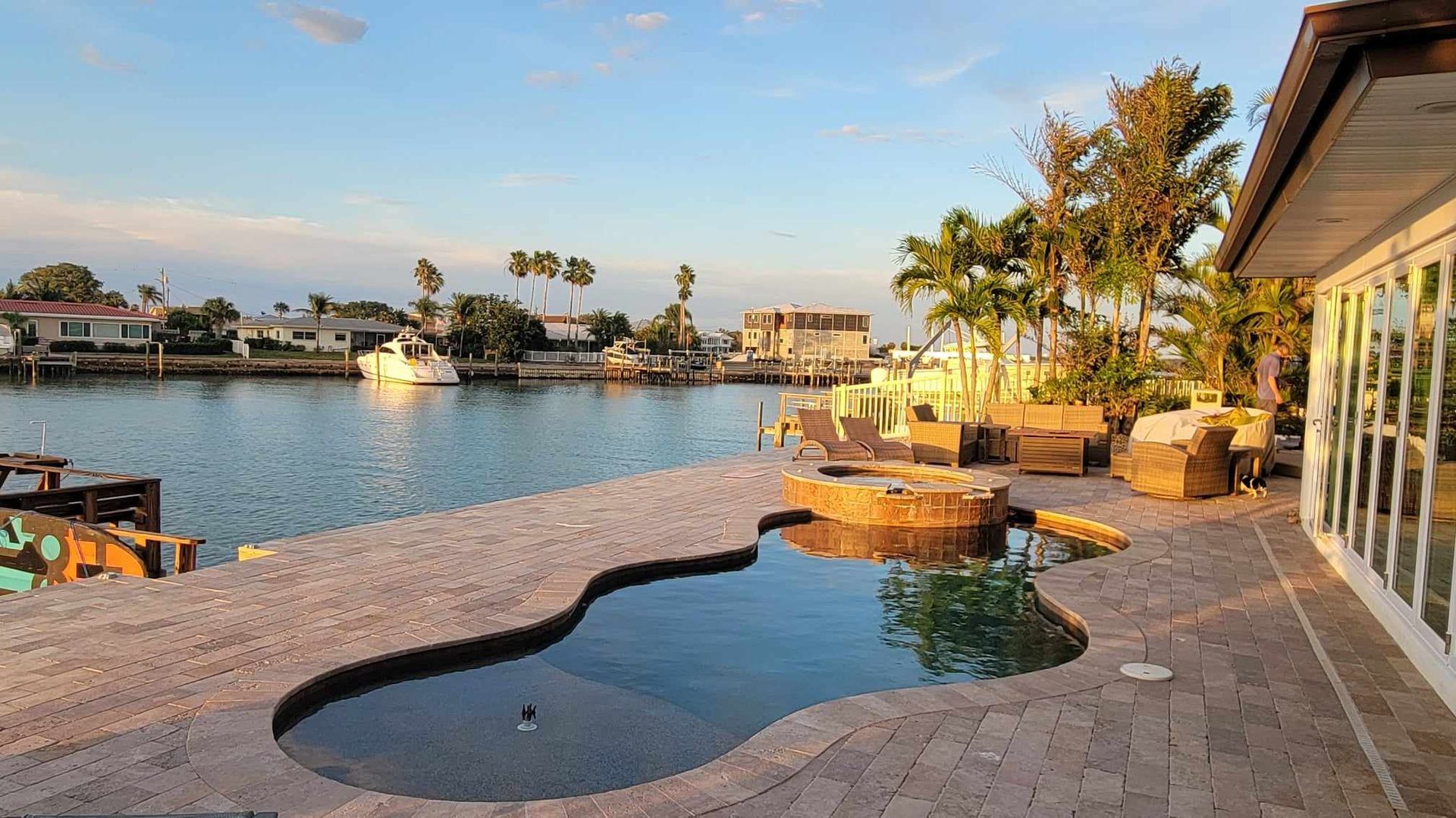 A large swimming pool is in the middle of a patio next to a body of water.