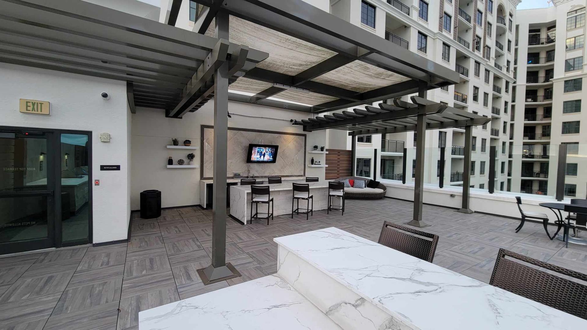 A large patio area with a table and chairs under a pergola.