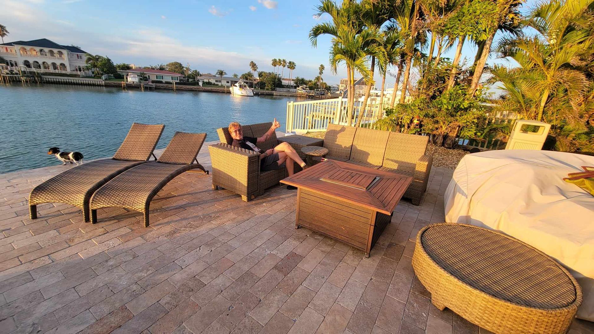 A man is sitting on a couch on a patio next to a body of water.
