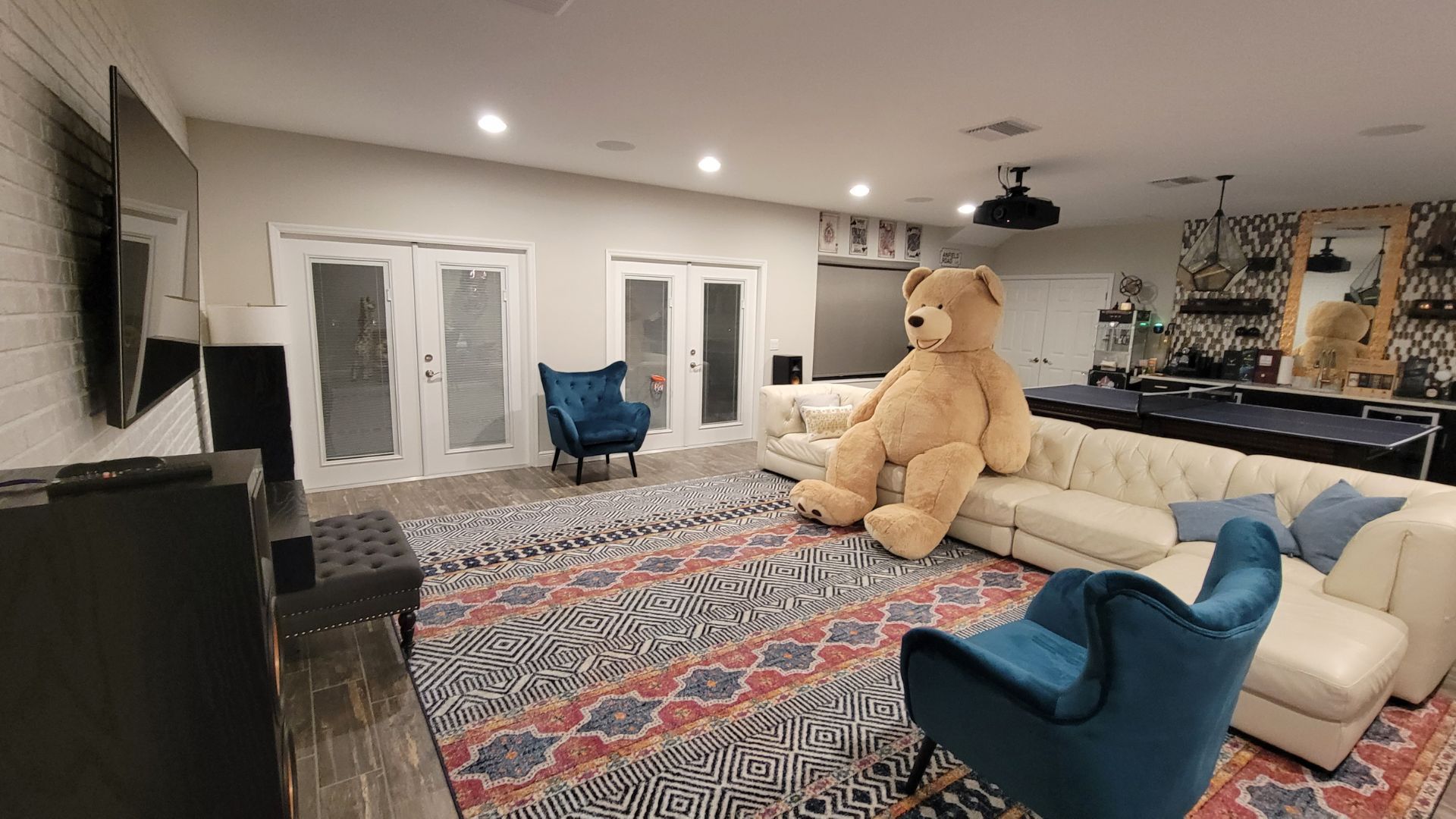 A large teddy bear is sitting on a couch in a living room.