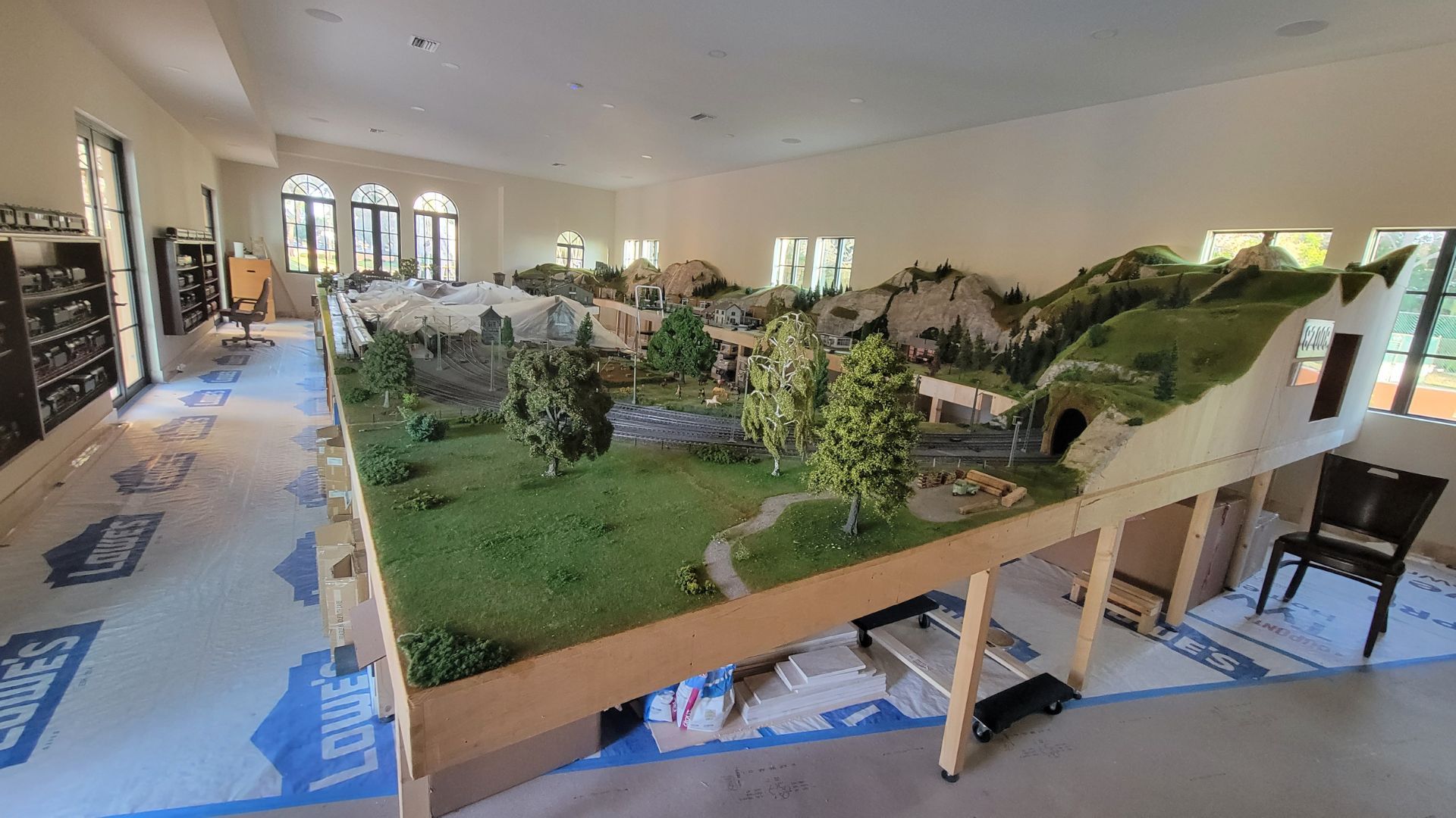 A large model train set is sitting on top of a wooden table in a room.