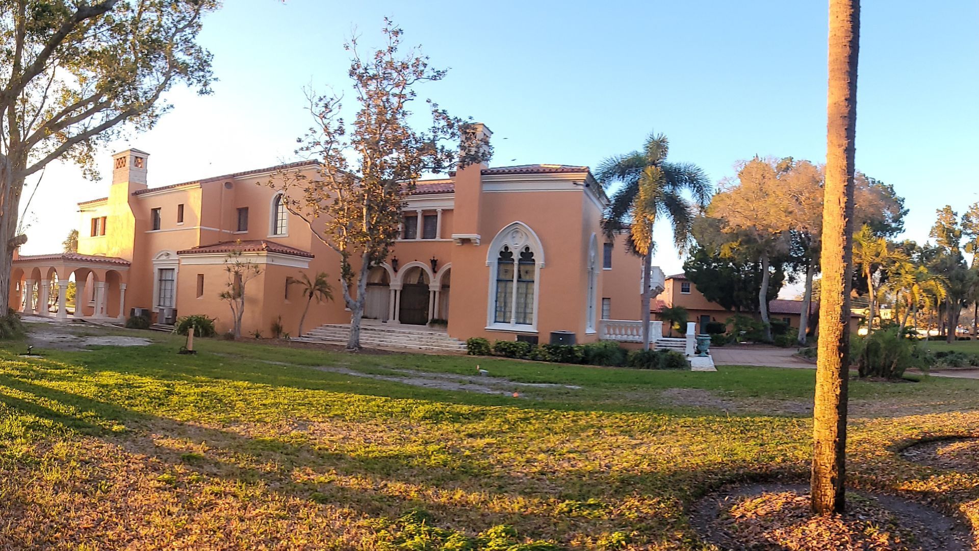 A large orange house with a palm tree in front of it