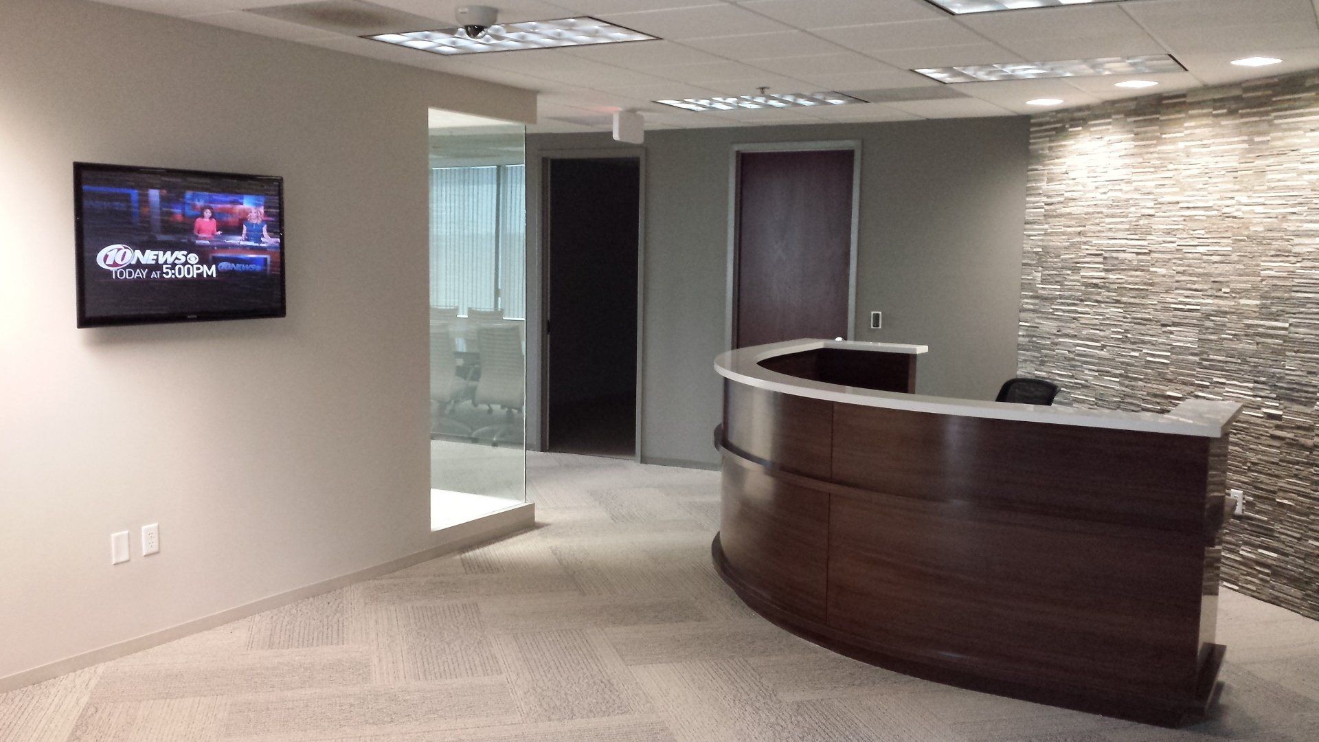 A reception area with a curved counter and a flat screen tv on the wall