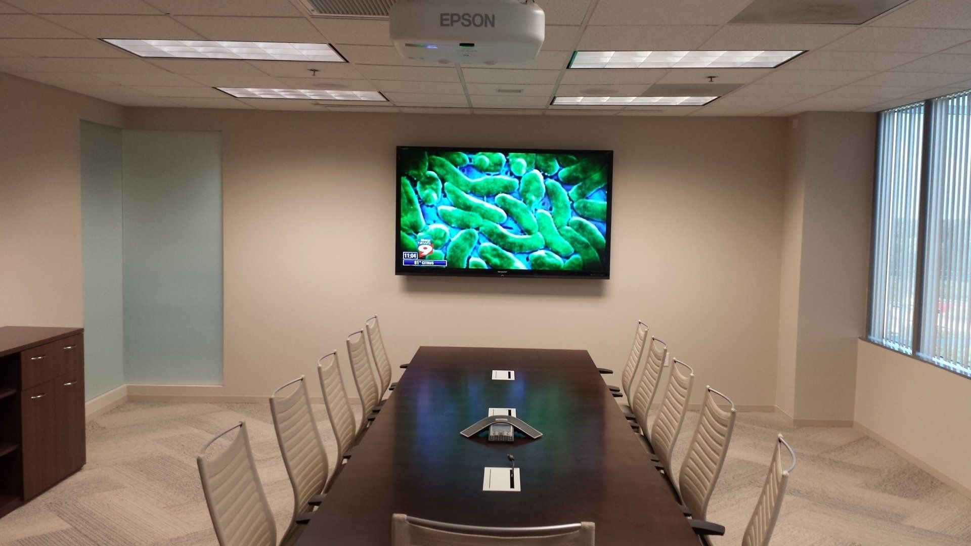 A conference room with a long table and chairs and a flat screen tv on the wall