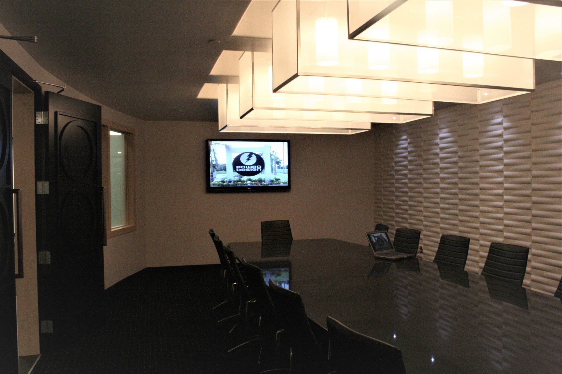 A conference room with a large table and chairs and a flat screen tv on the wall