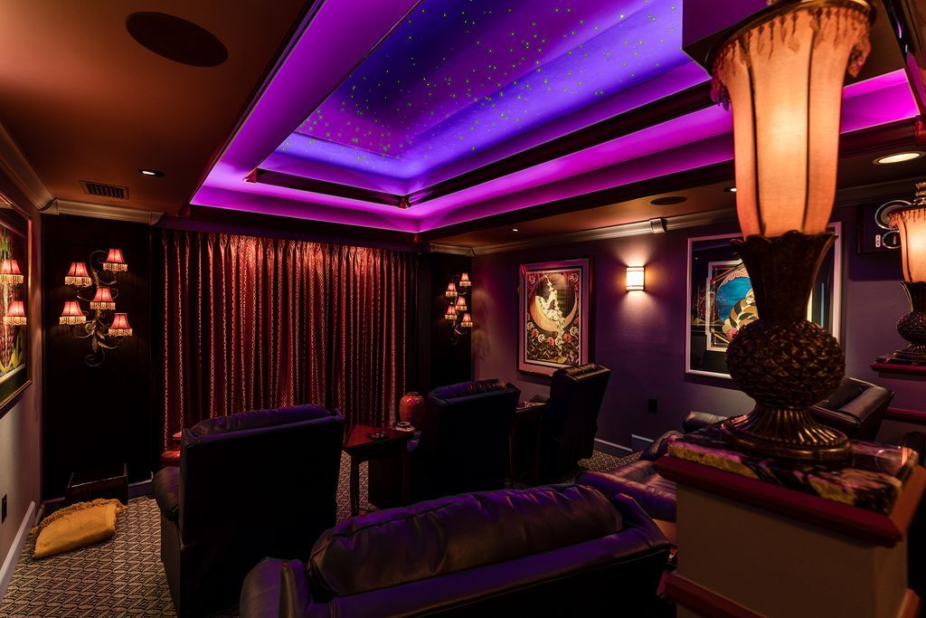 A living room with purple lights on the ceiling and a couch.