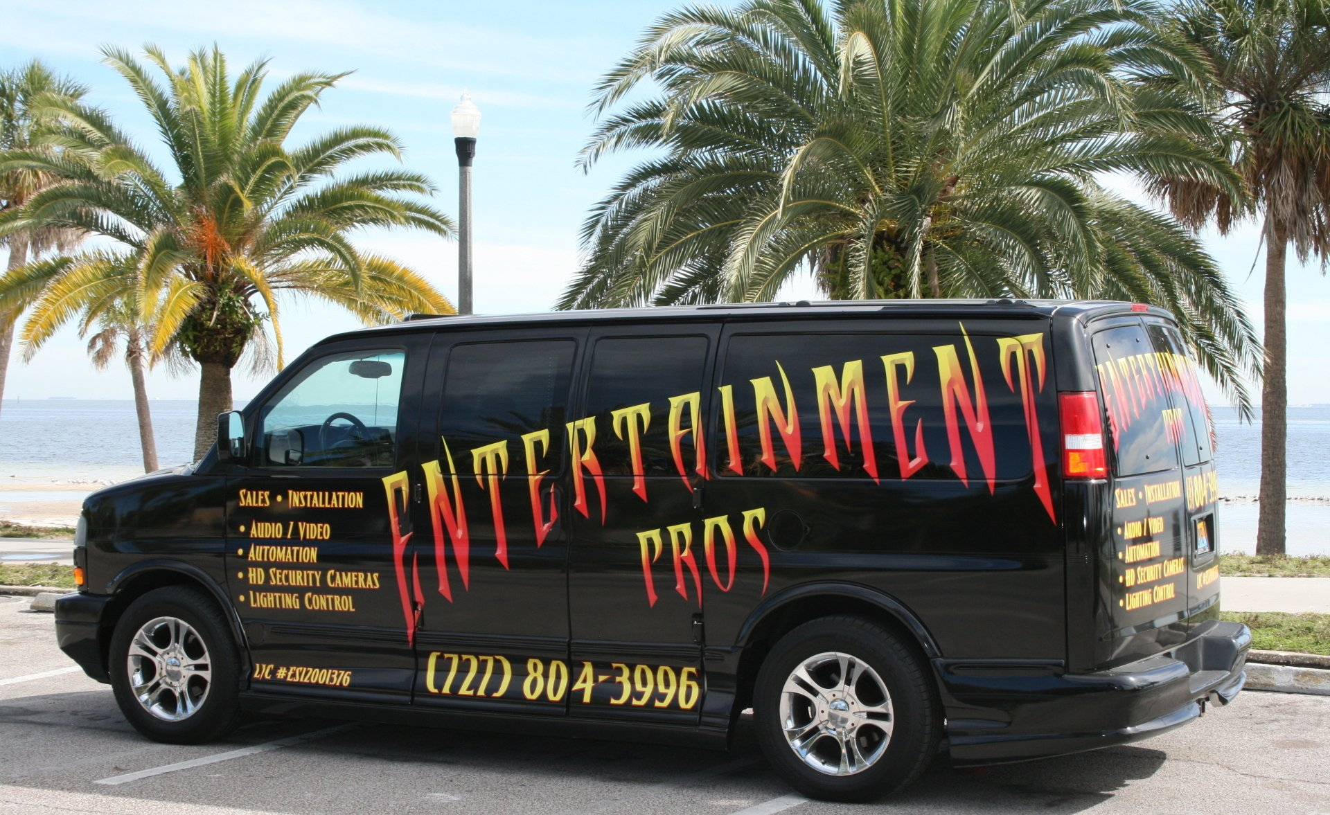 A black van that says entertainment pros is parked in front of palm trees