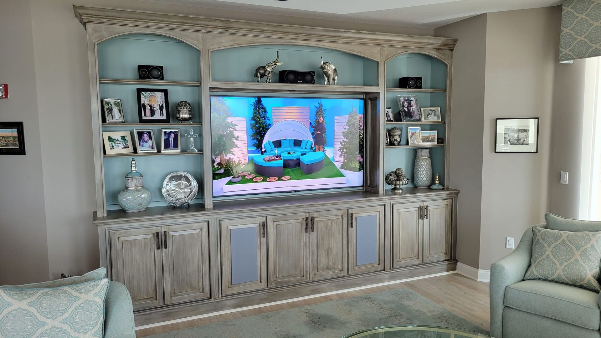 A living room with a large entertainment center and a flat screen tv.
