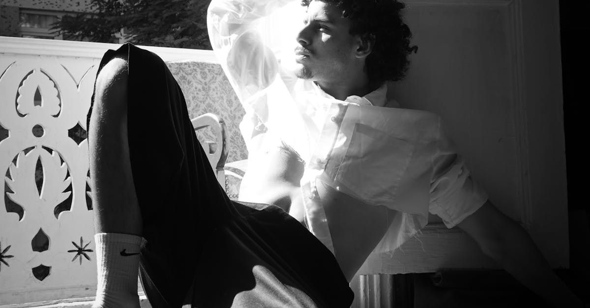 A black and white photo of a man sitting in front of a window.