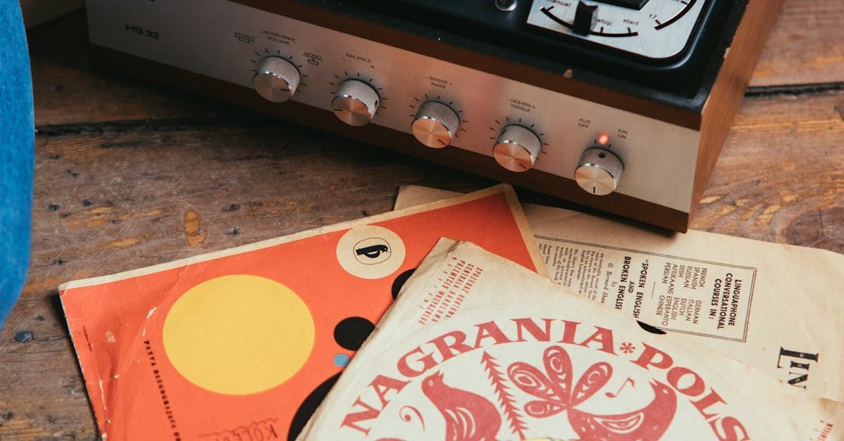 A record player is sitting on a wooden table next to some records.