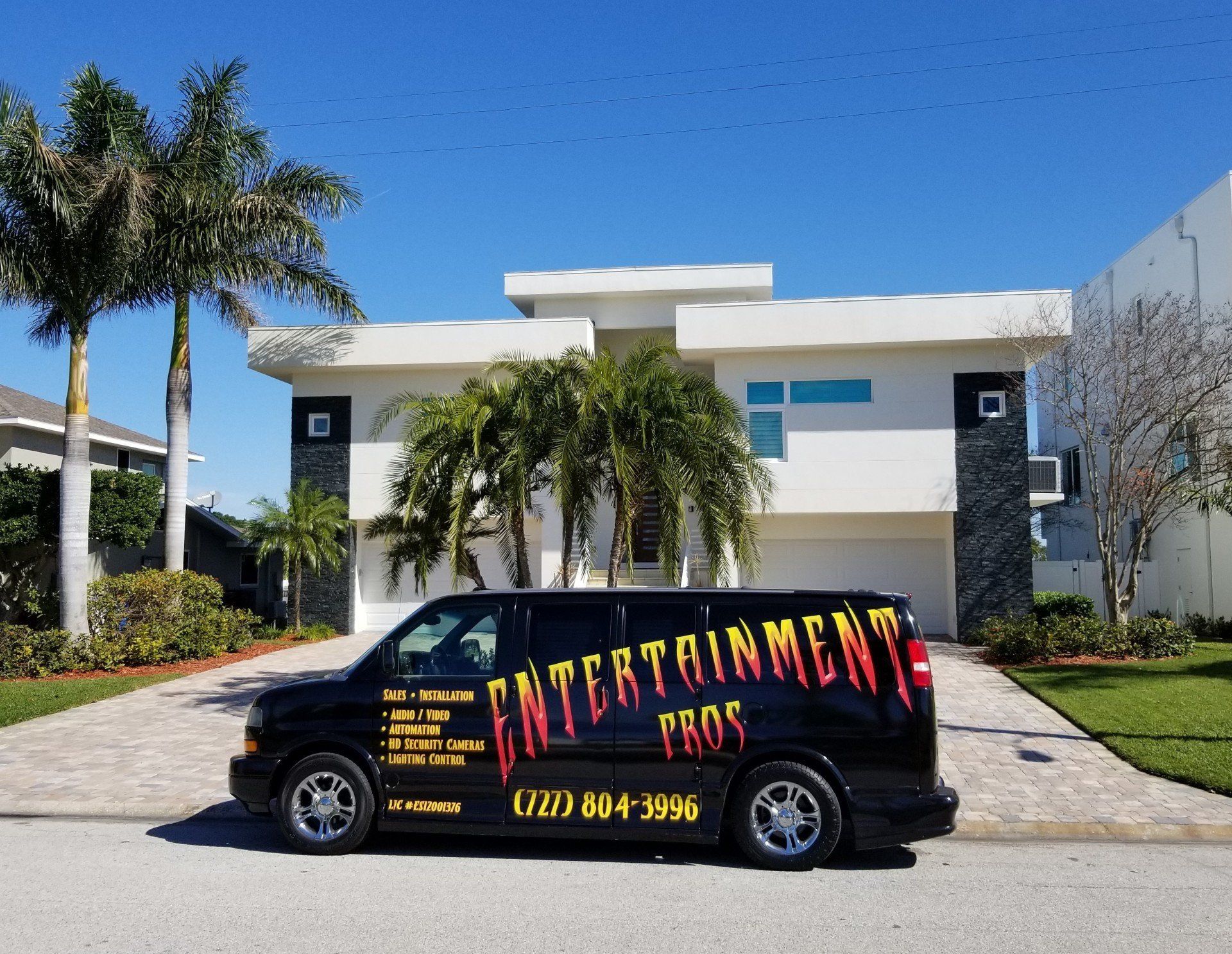 A van that says entertainment pros is parked in front of a house