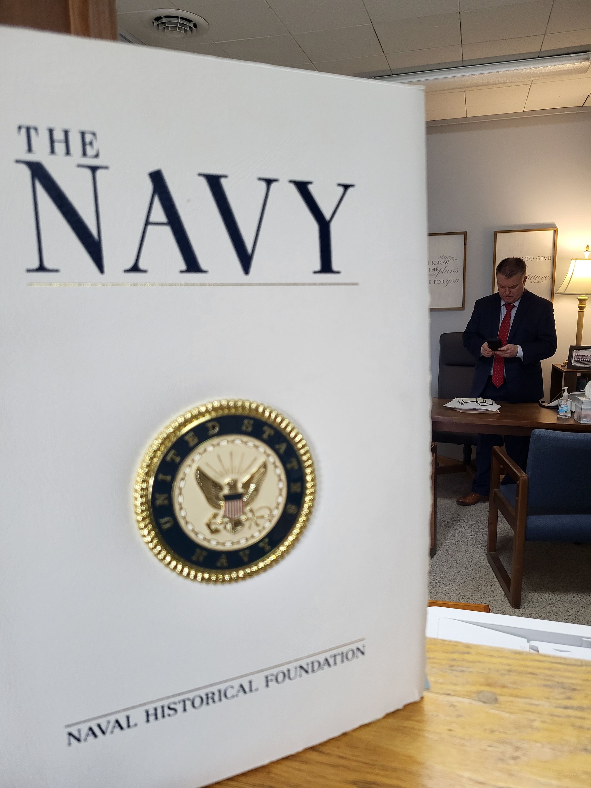 Brad Baber, Attorney in Columbia City and former Navy JAG, standing behind a white book titled
