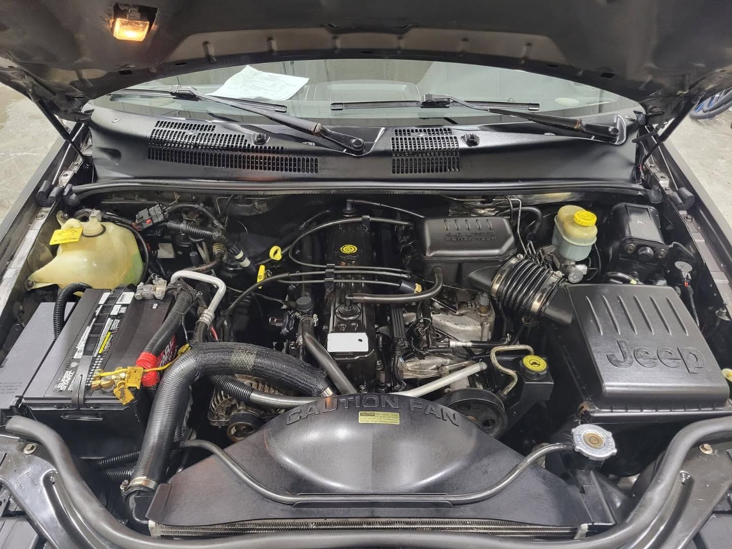 The engine of a jeep is shown with the hood open.