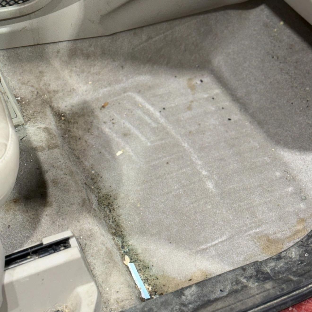 A close up of a dirty floor in a car.