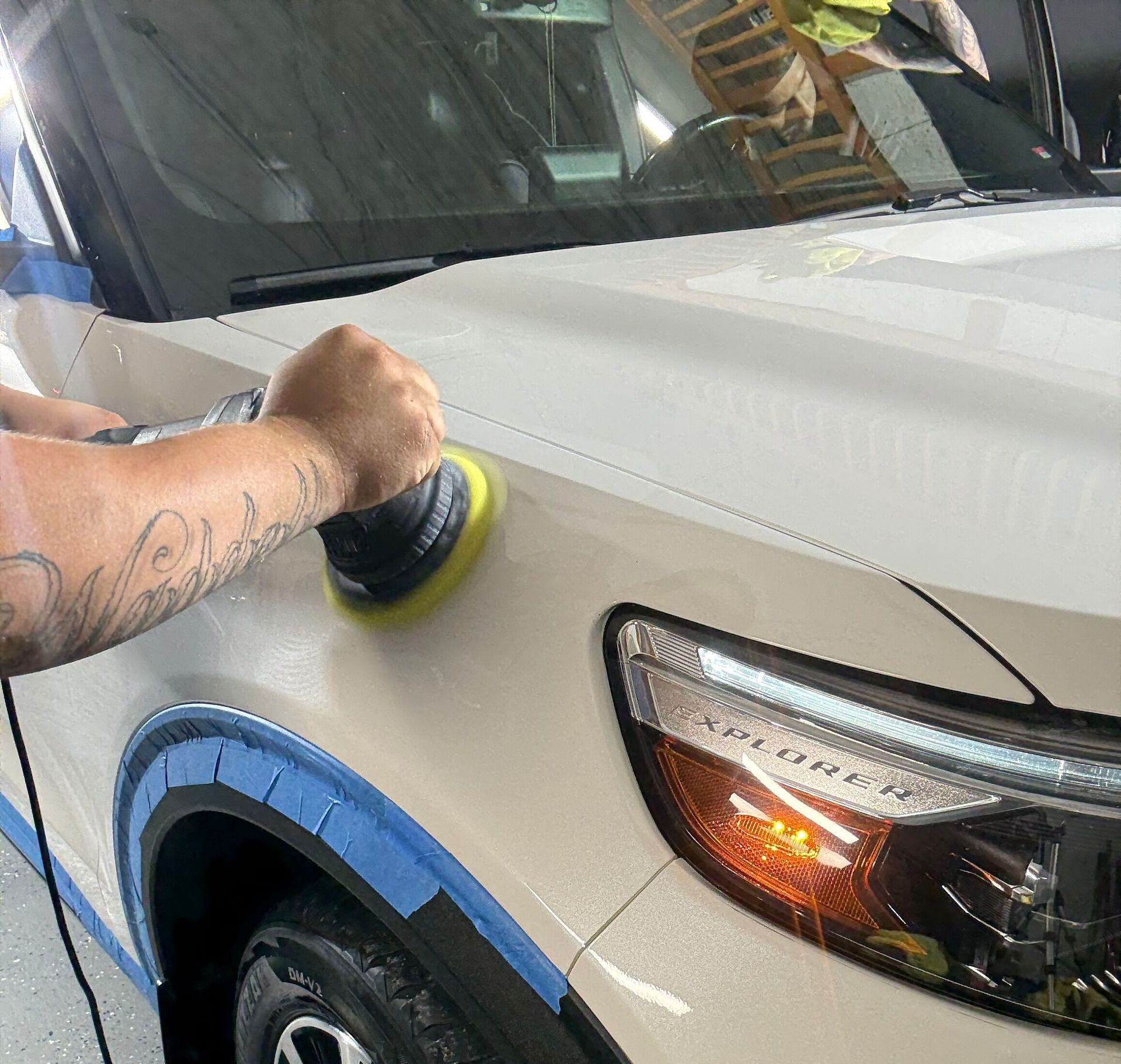A man is polishing the hood of a white car