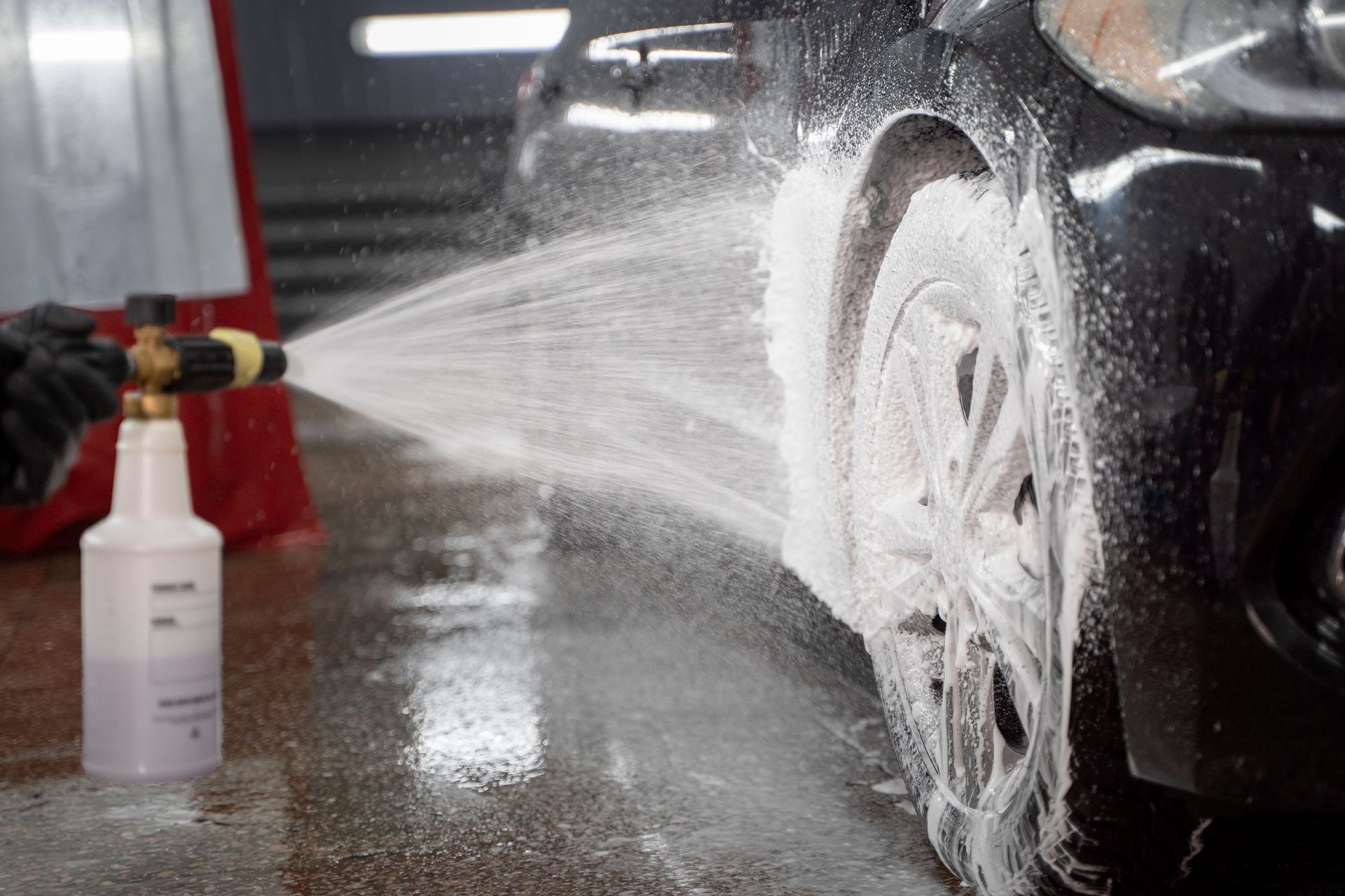 A person is spraying foam on a car wheel.