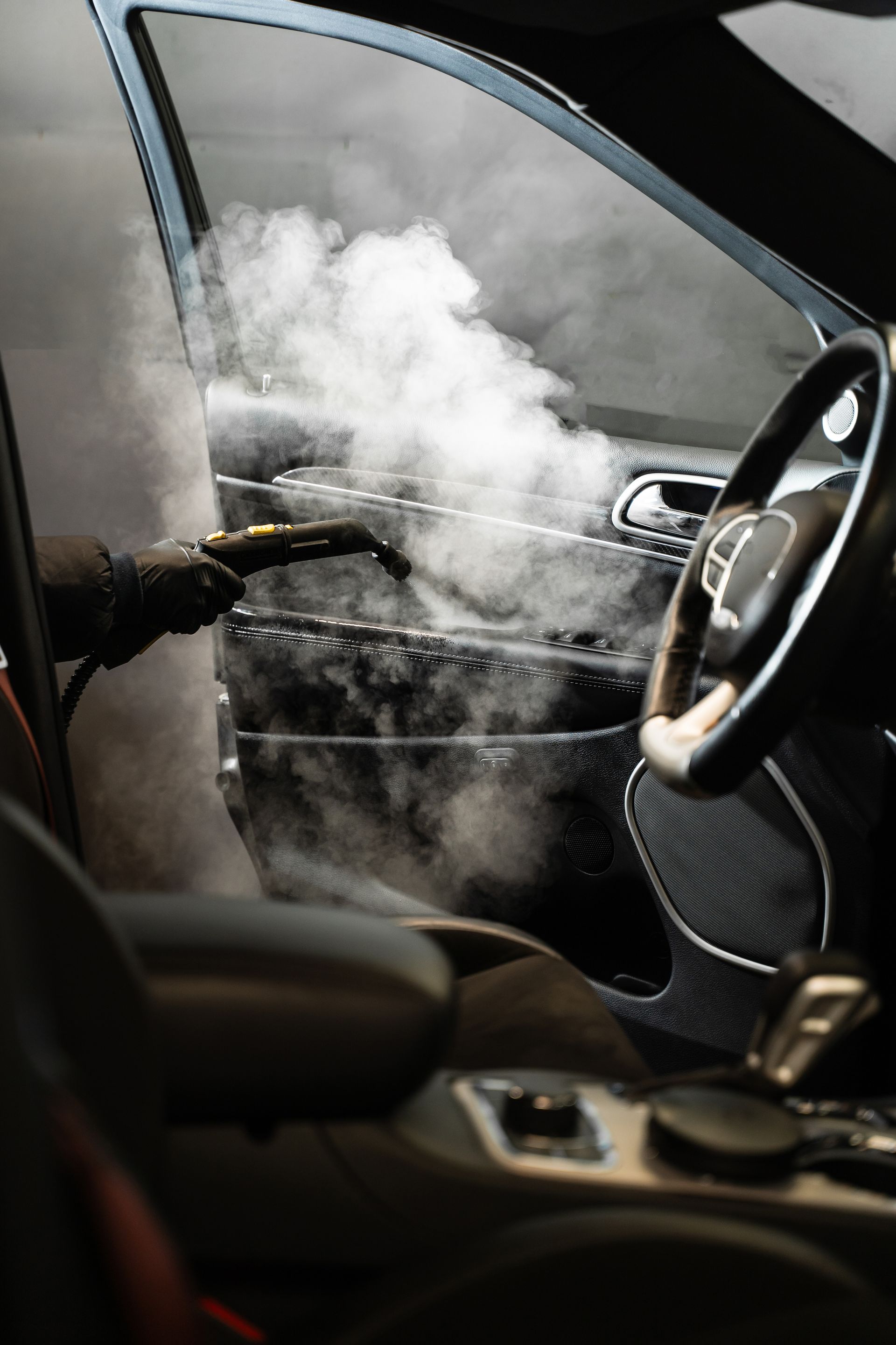 A car is being cleaned with a steam cleaner.