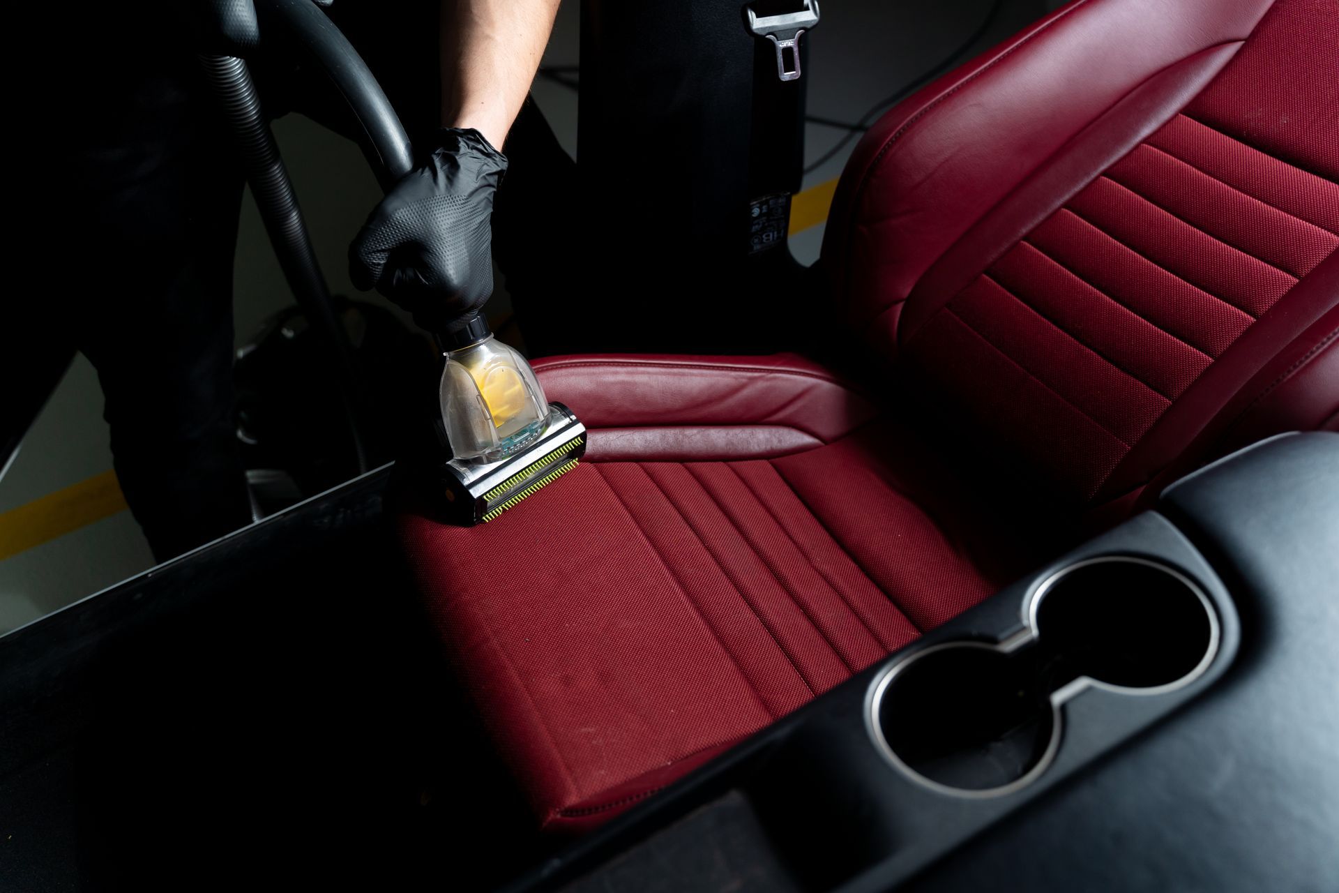 A person is cleaning a car seat with a vacuum cleaner.
