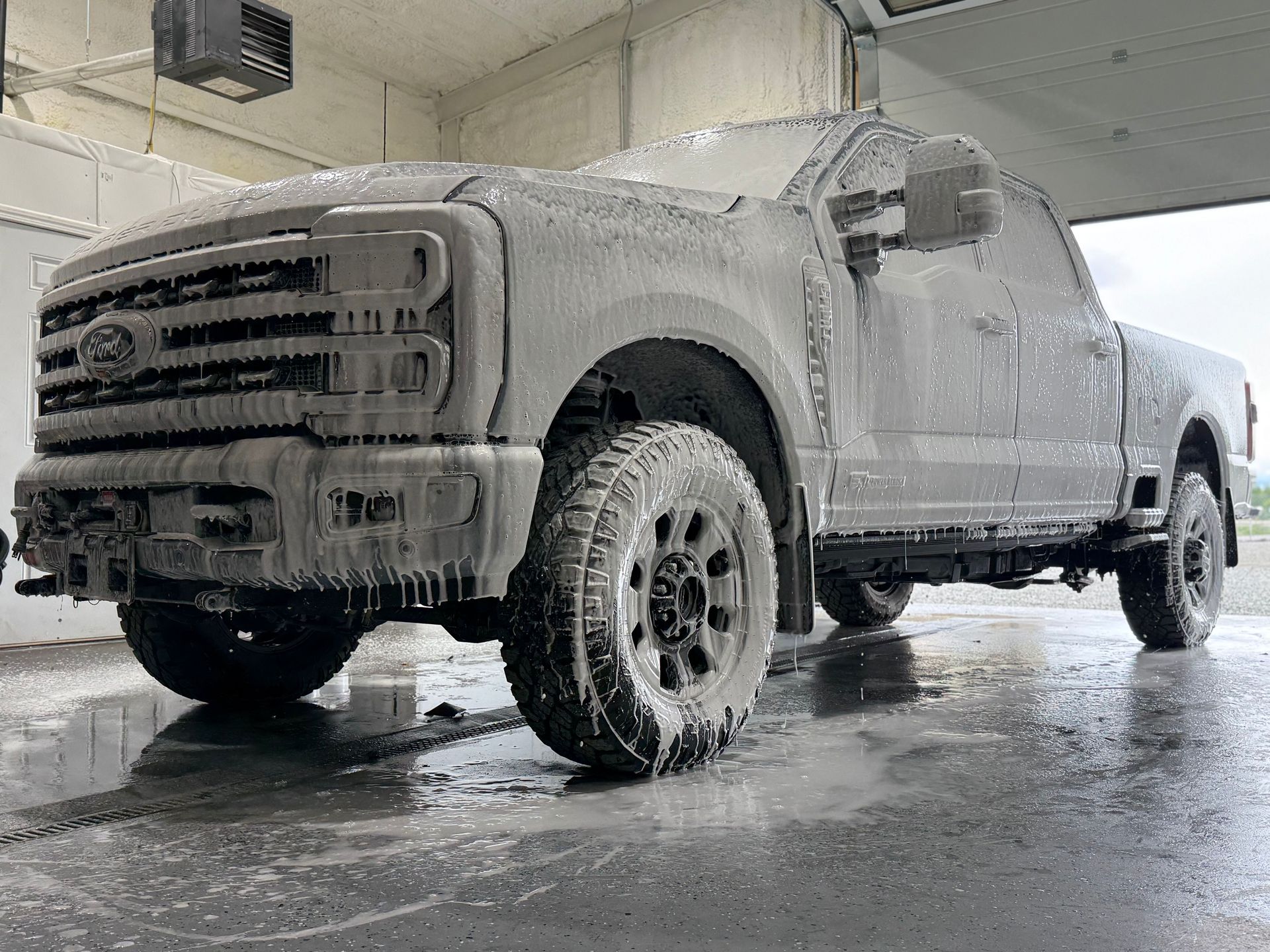 A ford truck is covered in foam at a car wash.