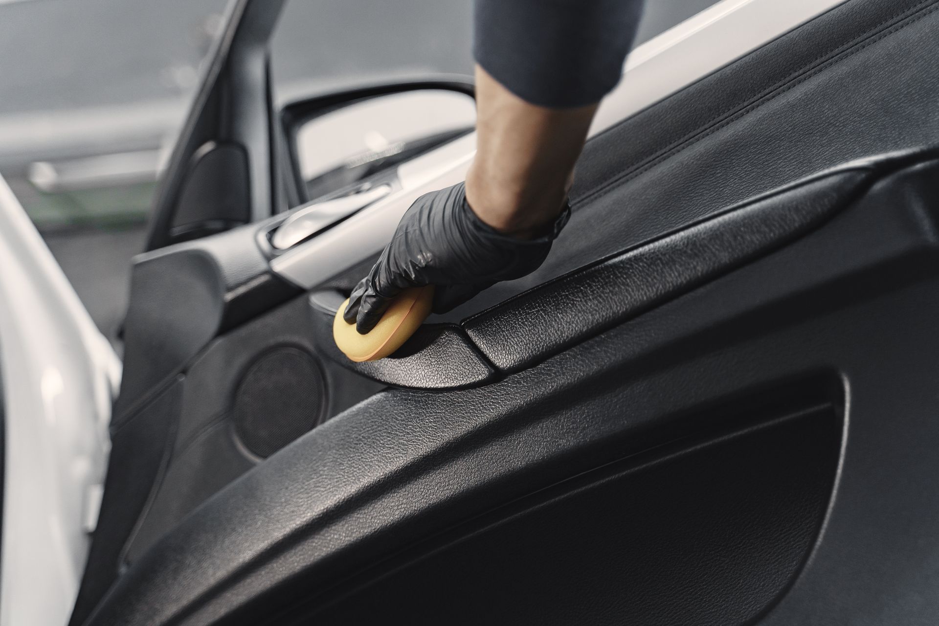 A person is cleaning the door of a car with a sponge.