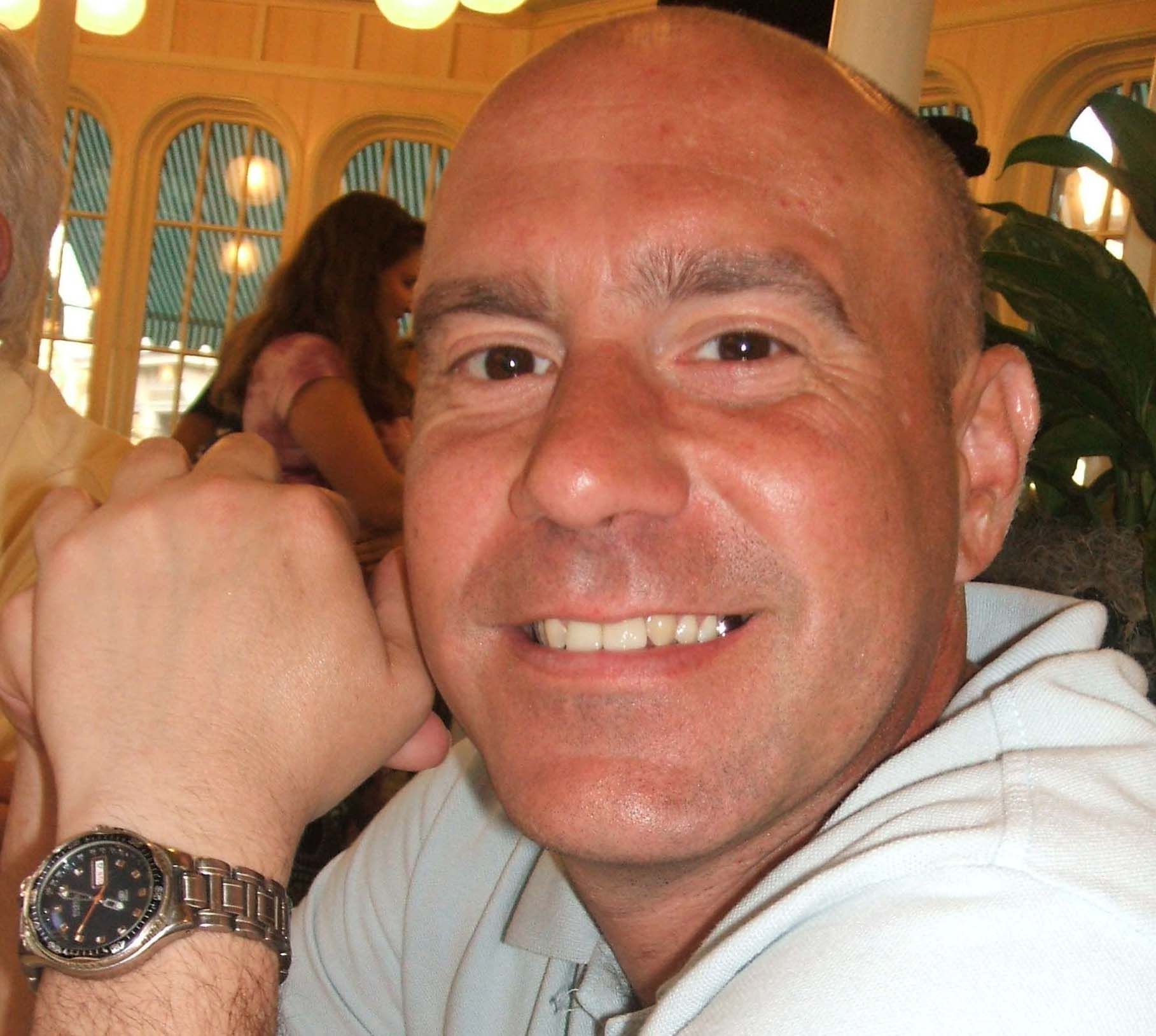 A man wearing a watch on his wrist smiles for the camera