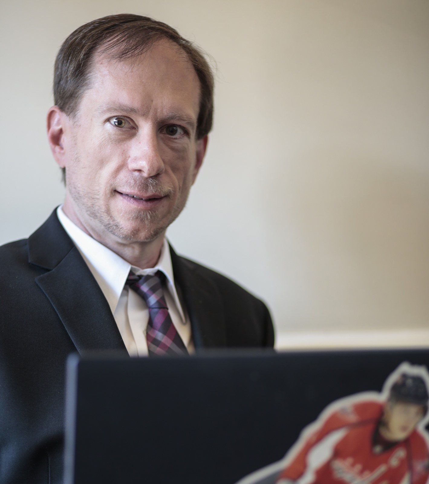 A man in a suit and tie is sitting in front of a laptop computer.