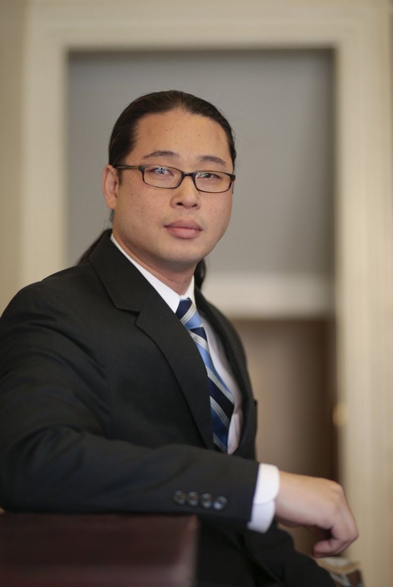 A man in a suit and tie is leaning on a counter.