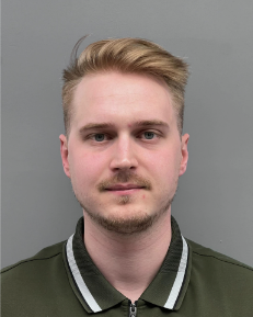 A young man with a beard is wearing a green polo shirt.