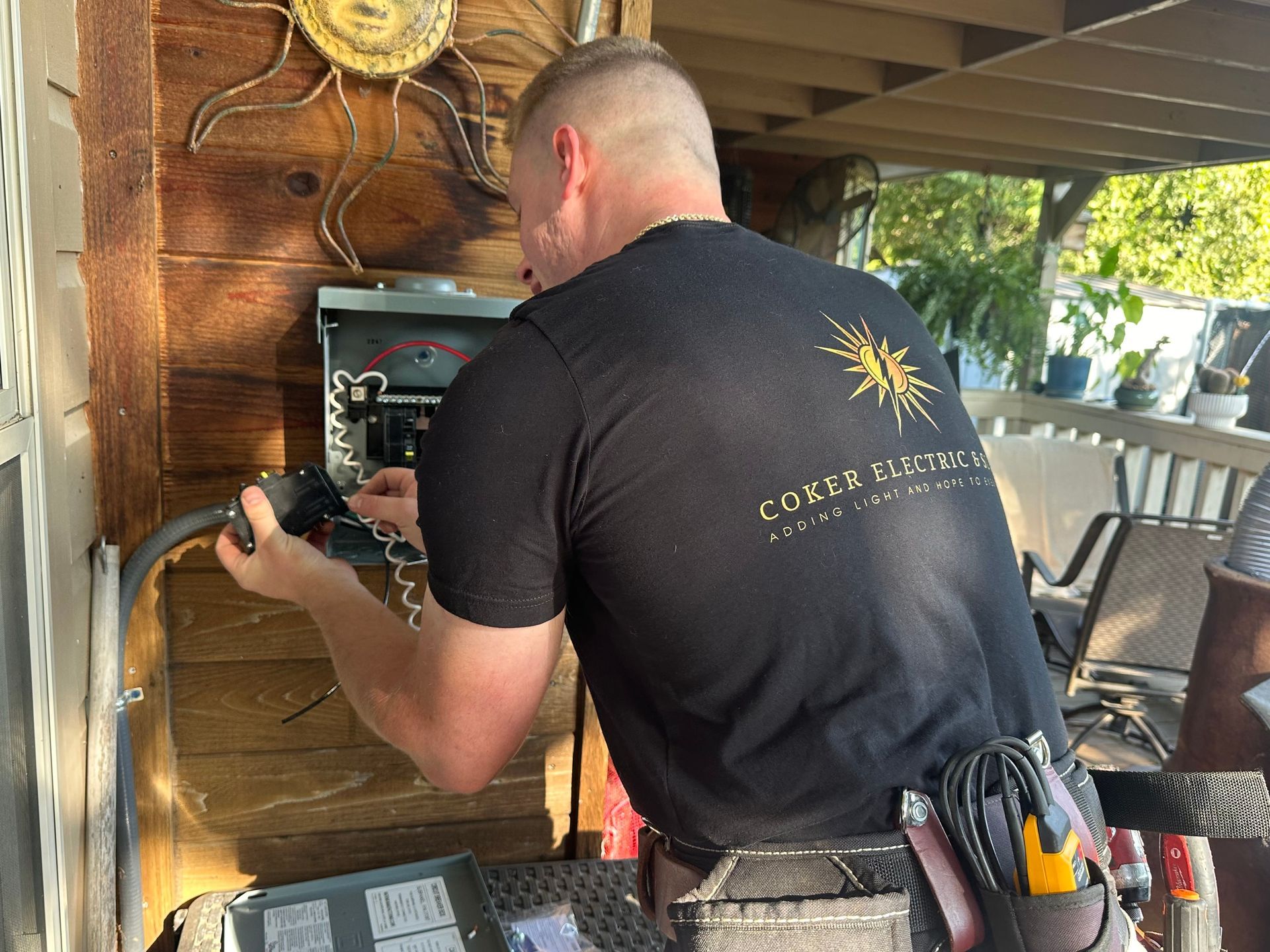 A man in a black shirt is working on an electrical box.