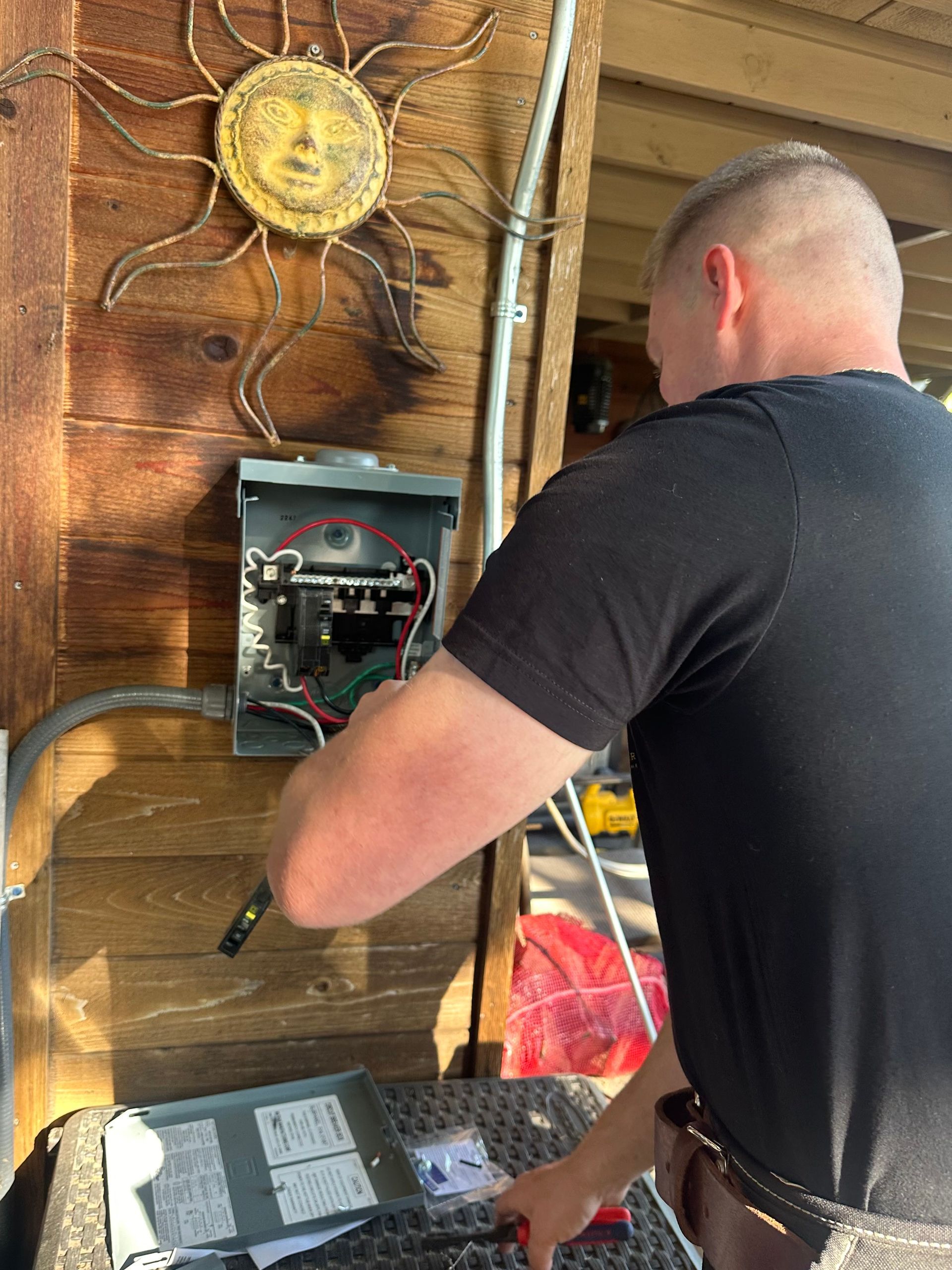A man is working on an electrical box on the side of a building.