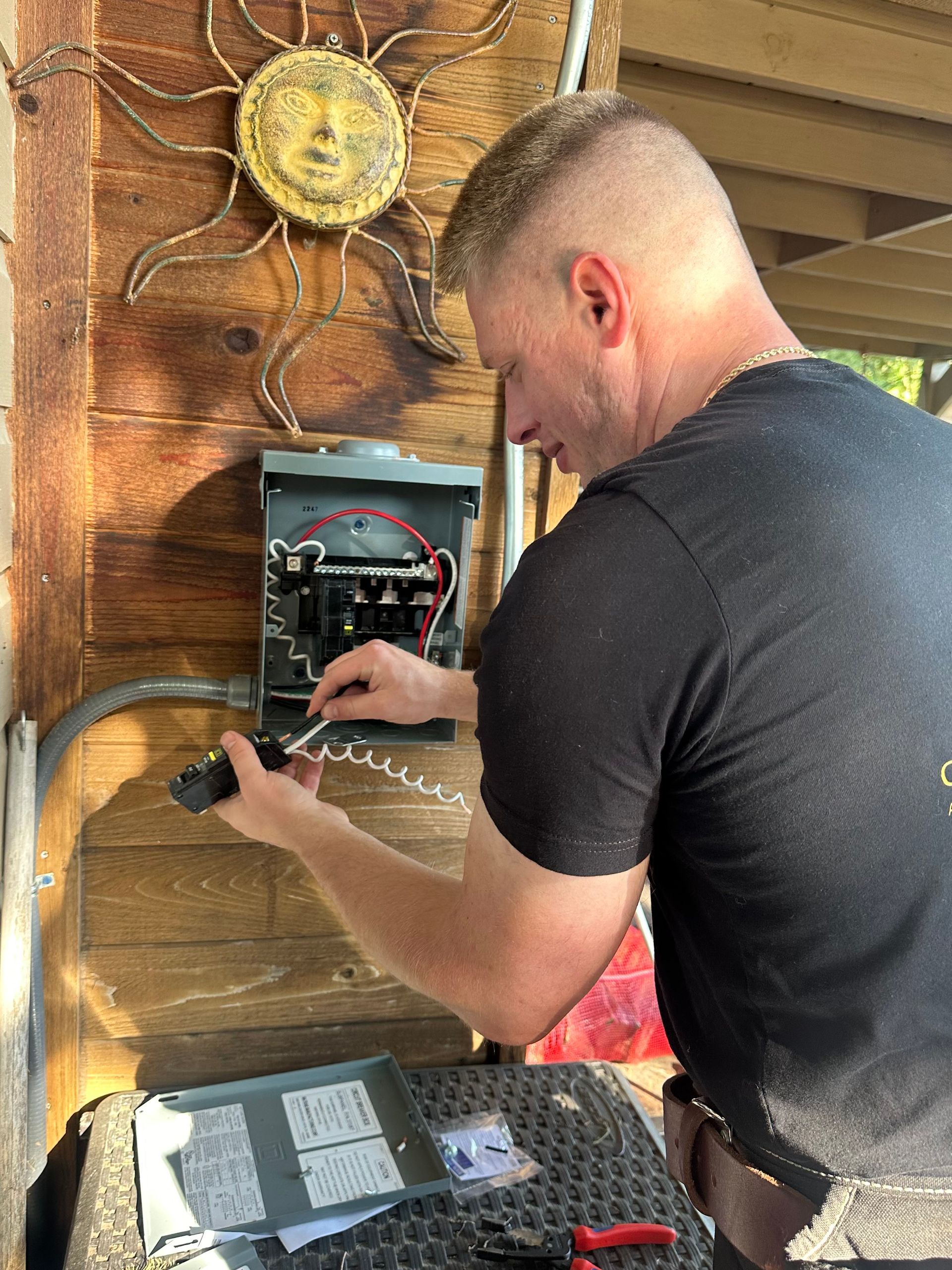 A man is working on an electrical box outside of a house.