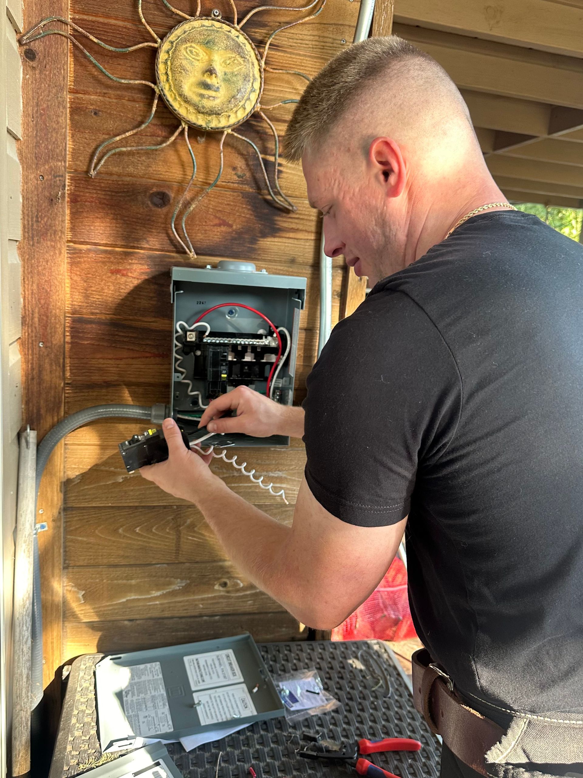 A man is working on an electrical box on the side of a building.