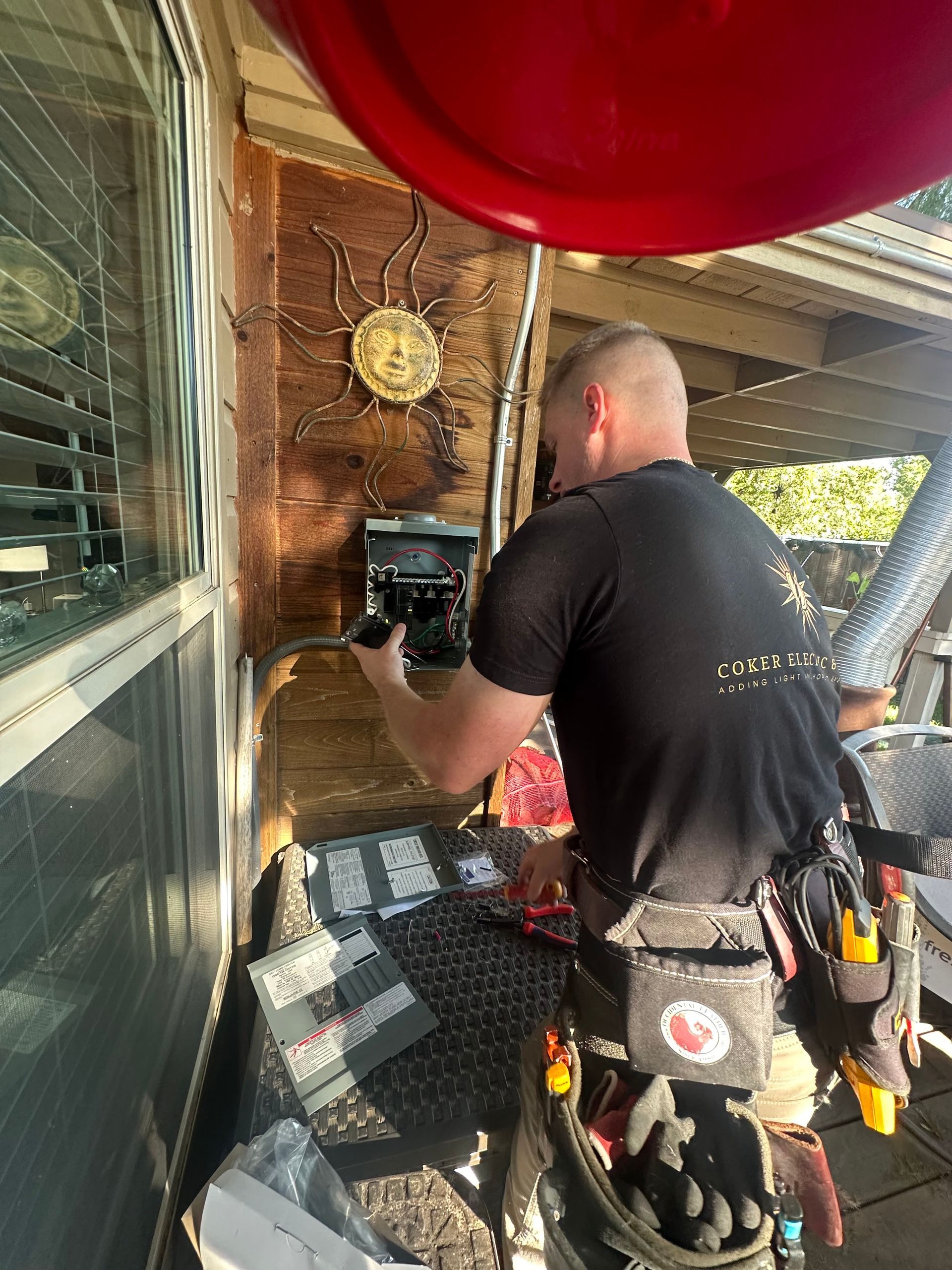 A man is working on a mailbox on the side of a house.