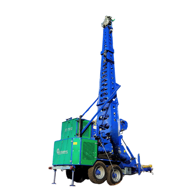 Piattaforma di perforazione blu e verde su ruote, utilizzata per la costruzione di pozzi o per l'attività mineraria.