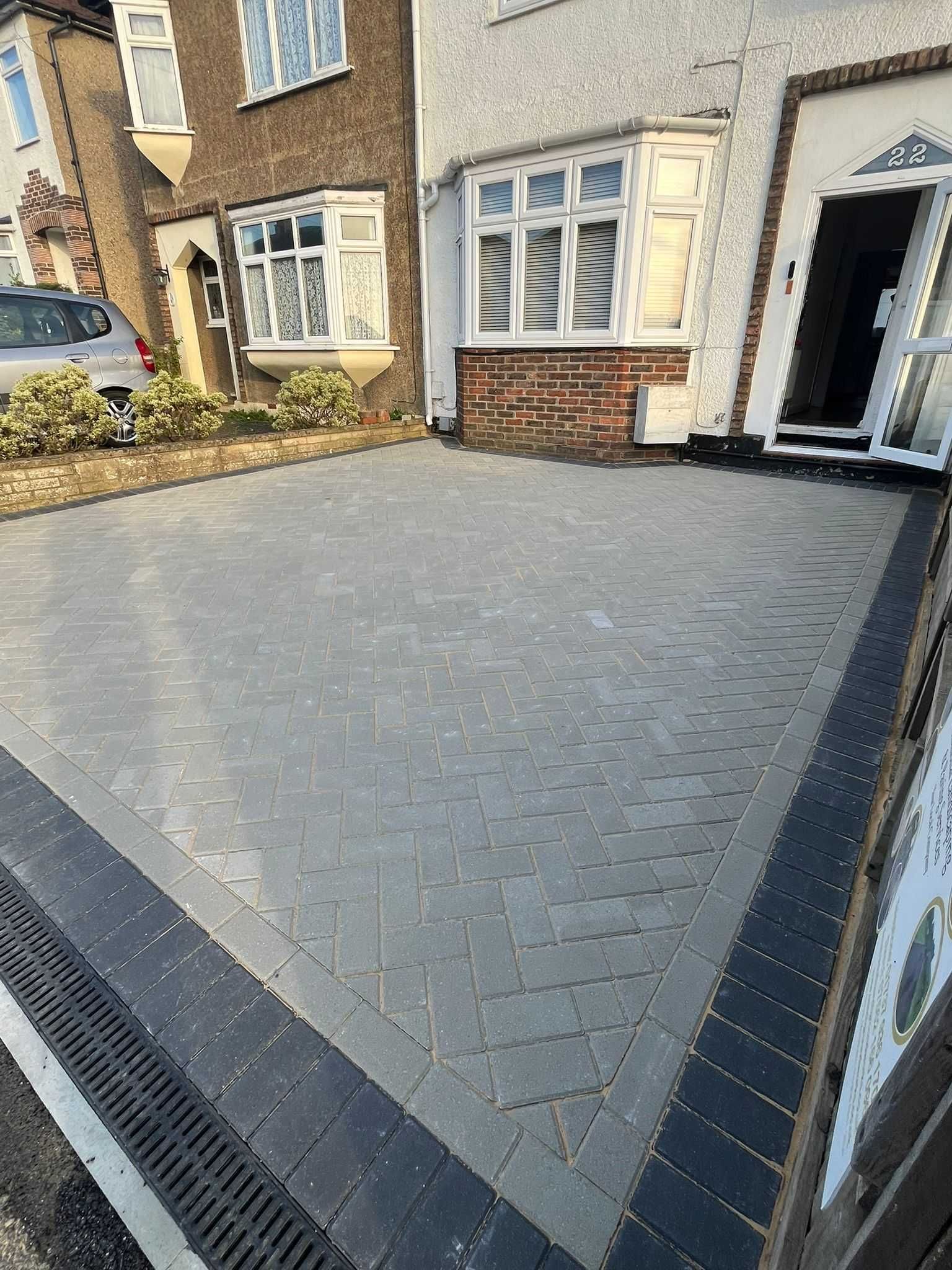 Houses with colorful exteriors and a brick driveway on a cloudy day.