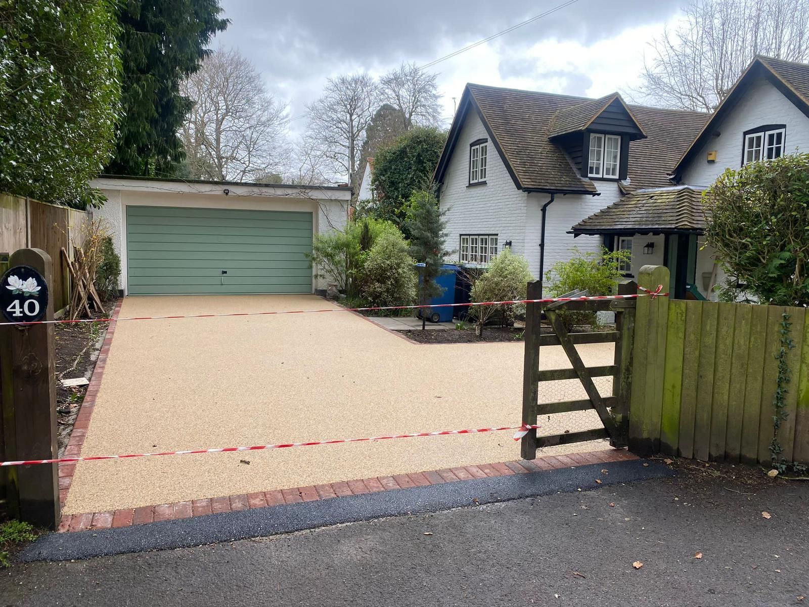 Driveway with gravel surface leading to a house with white exterior and a garage.