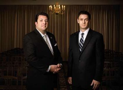 Two men in suits and ties are standing next to each other in a room.