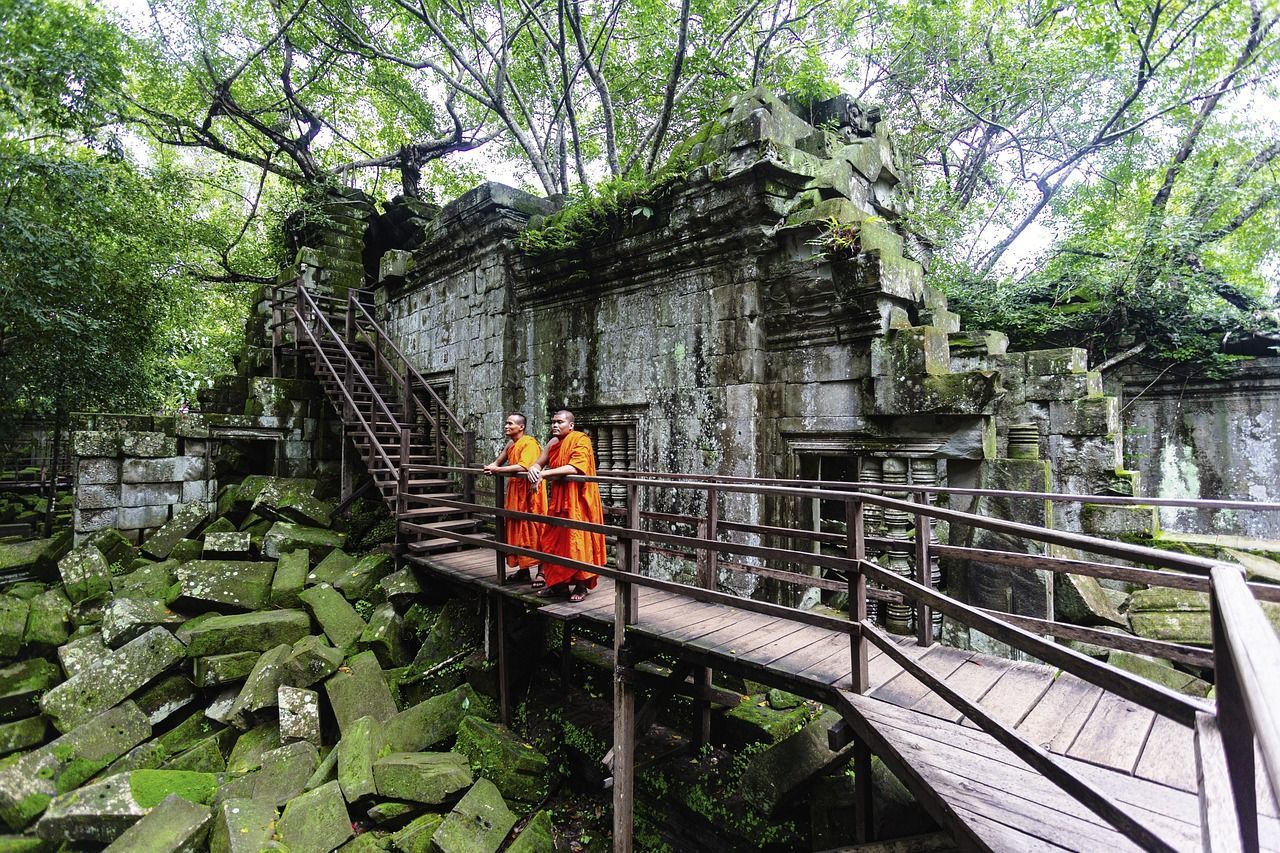 Two Buddhist monks standing outside an ancient Cambodian temple, symbolizing spiritual reflection