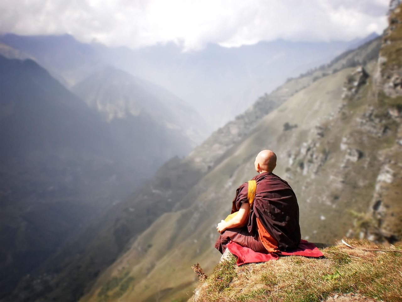 Buddhist monk sitting on a mountain next to a cliff