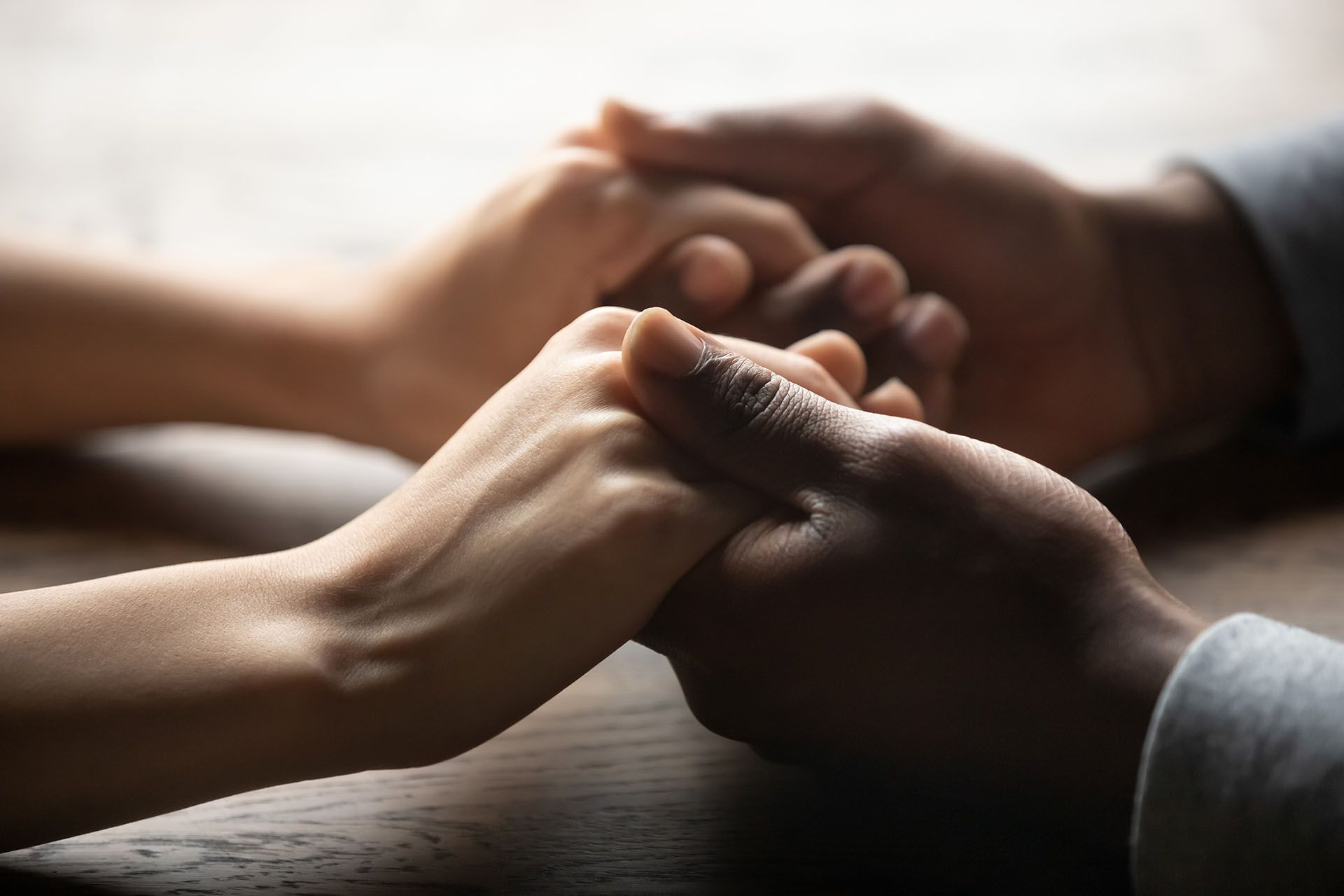 A man and a woman are holding hands on a wooden table.