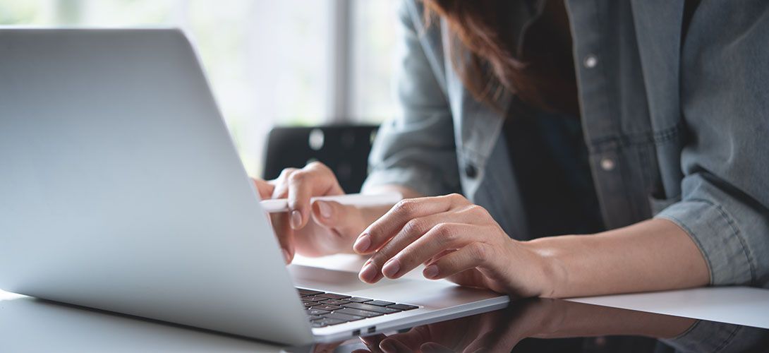 A woman is typing on a laptop computer while sitting at a table.