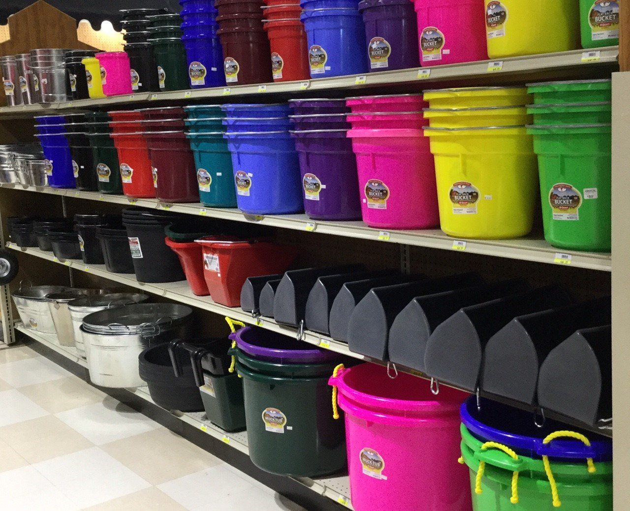 Various colored animal feed buckets that have been stacked on the store shelves