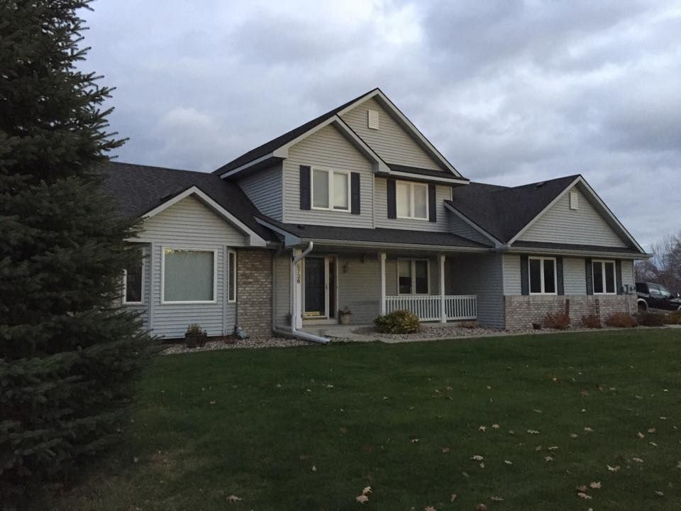 A large white house with a black roof and shutters