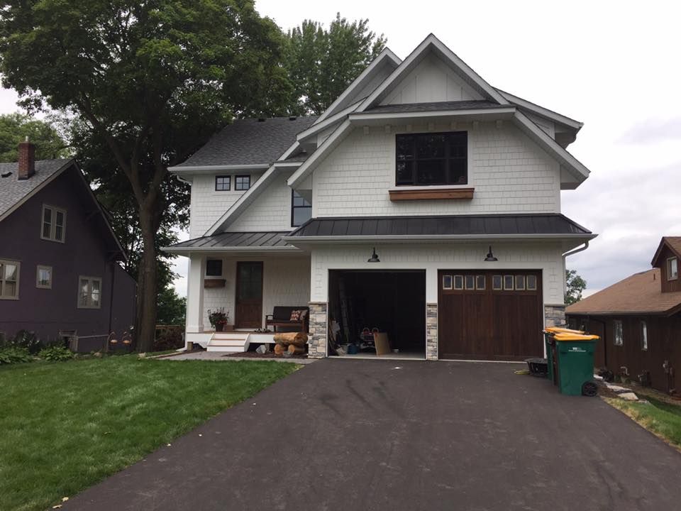 A white house with a garage and a purple house in the background