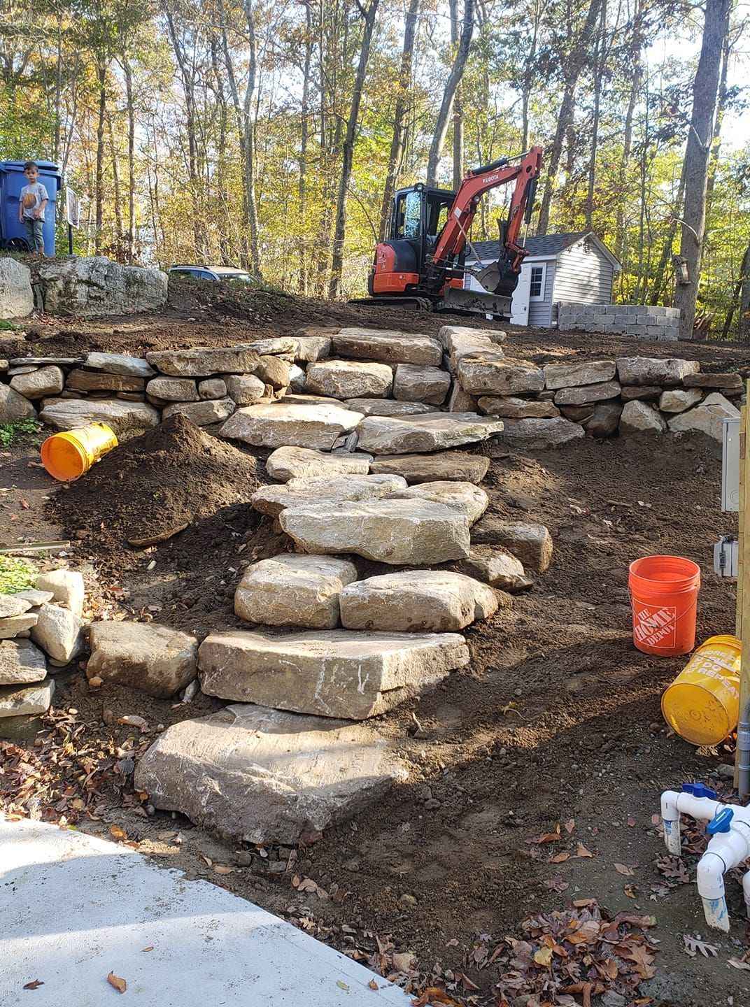 A stone wall is being built with a bulldozer in the background.