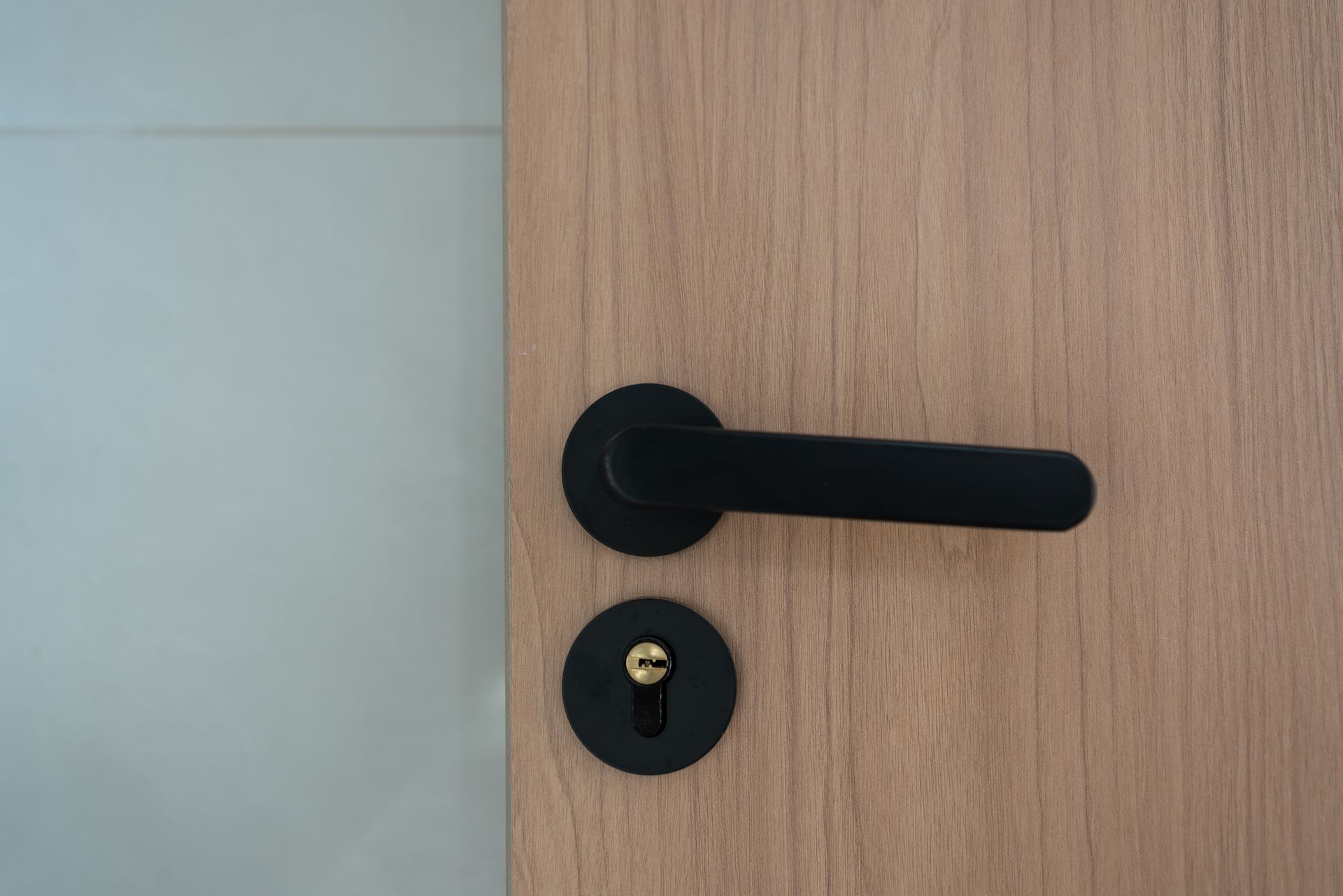 Close-up of a wooden door with a black handle and keyhole.