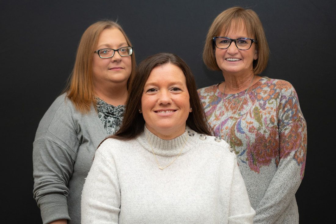 Three women are posing for a picture together and smiling for the camera.