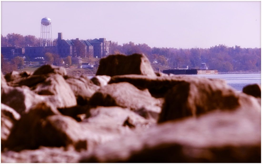 A rocky shoreline with a water tower in the background