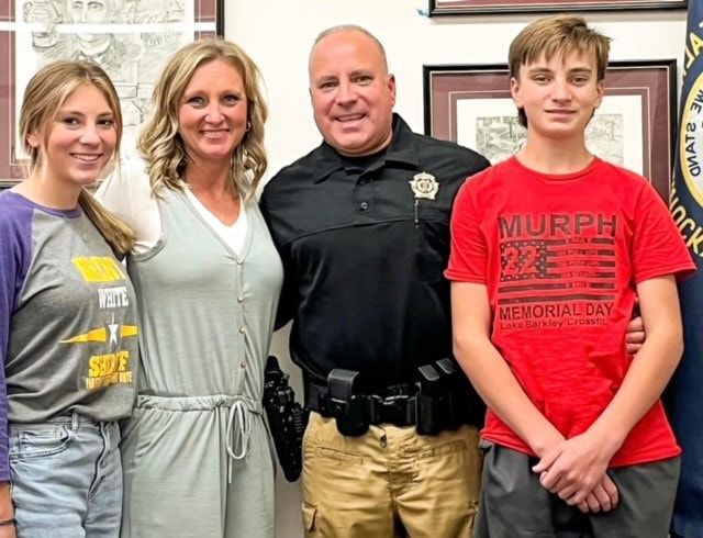 A family posing for a picture with a man in a murphy shirt